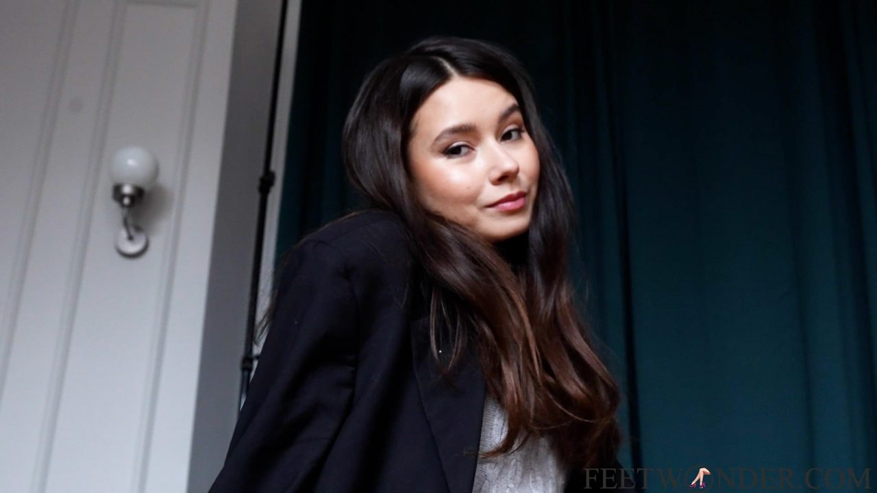 Naomi the asian foot model in black blazer leaning against a doorway
